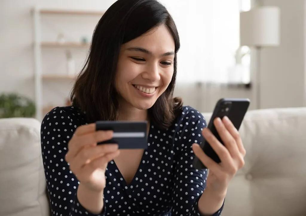 A person using a smartphone and payment card, illustrating Western Union and Visa Direct cross-border money transfers to eligible cards.