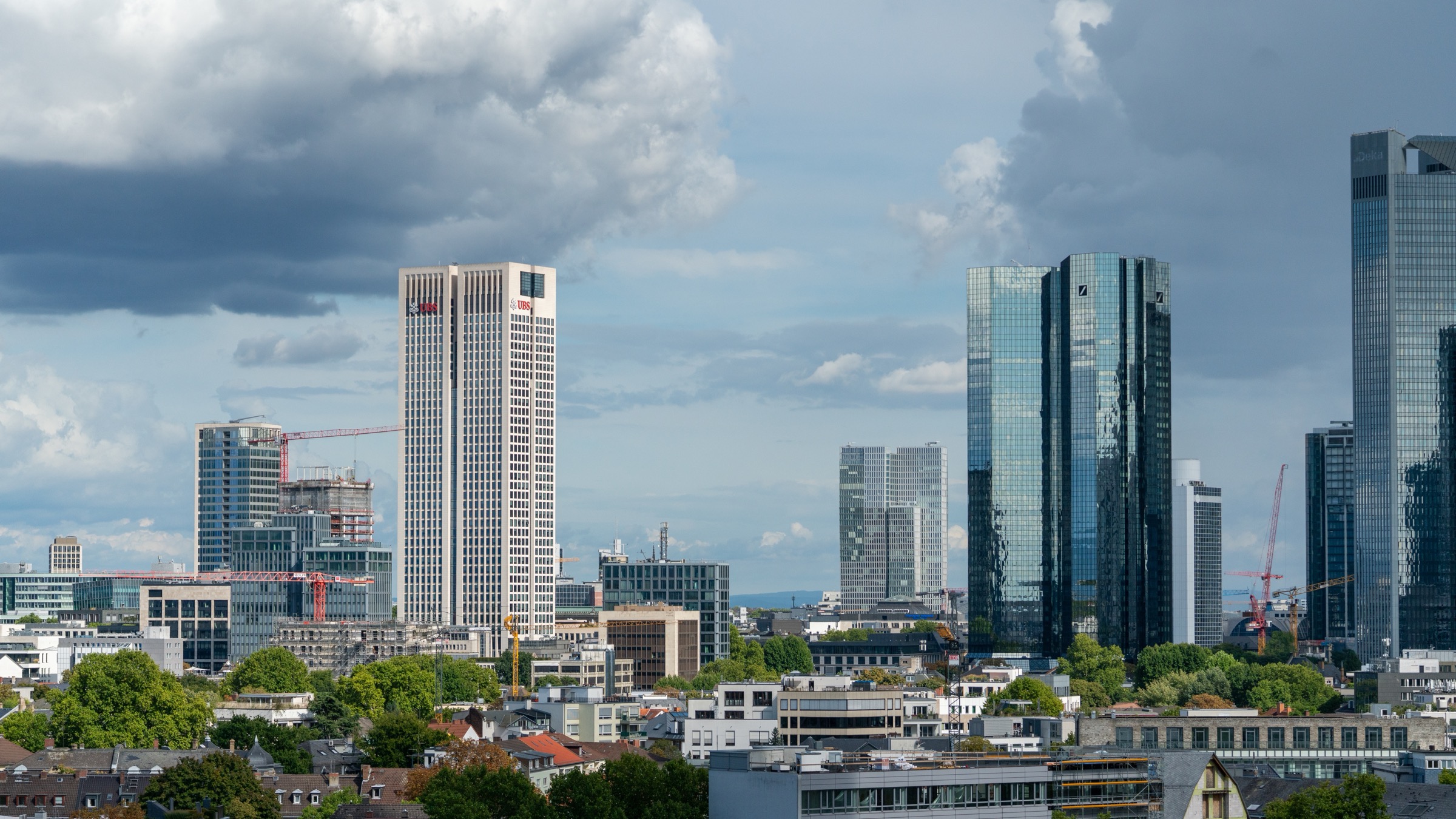 The Frankfurt banking skyline, with a UBS sign near the top of the white Opernturm at left and the dark twin towers of Deutsche Bank at right.