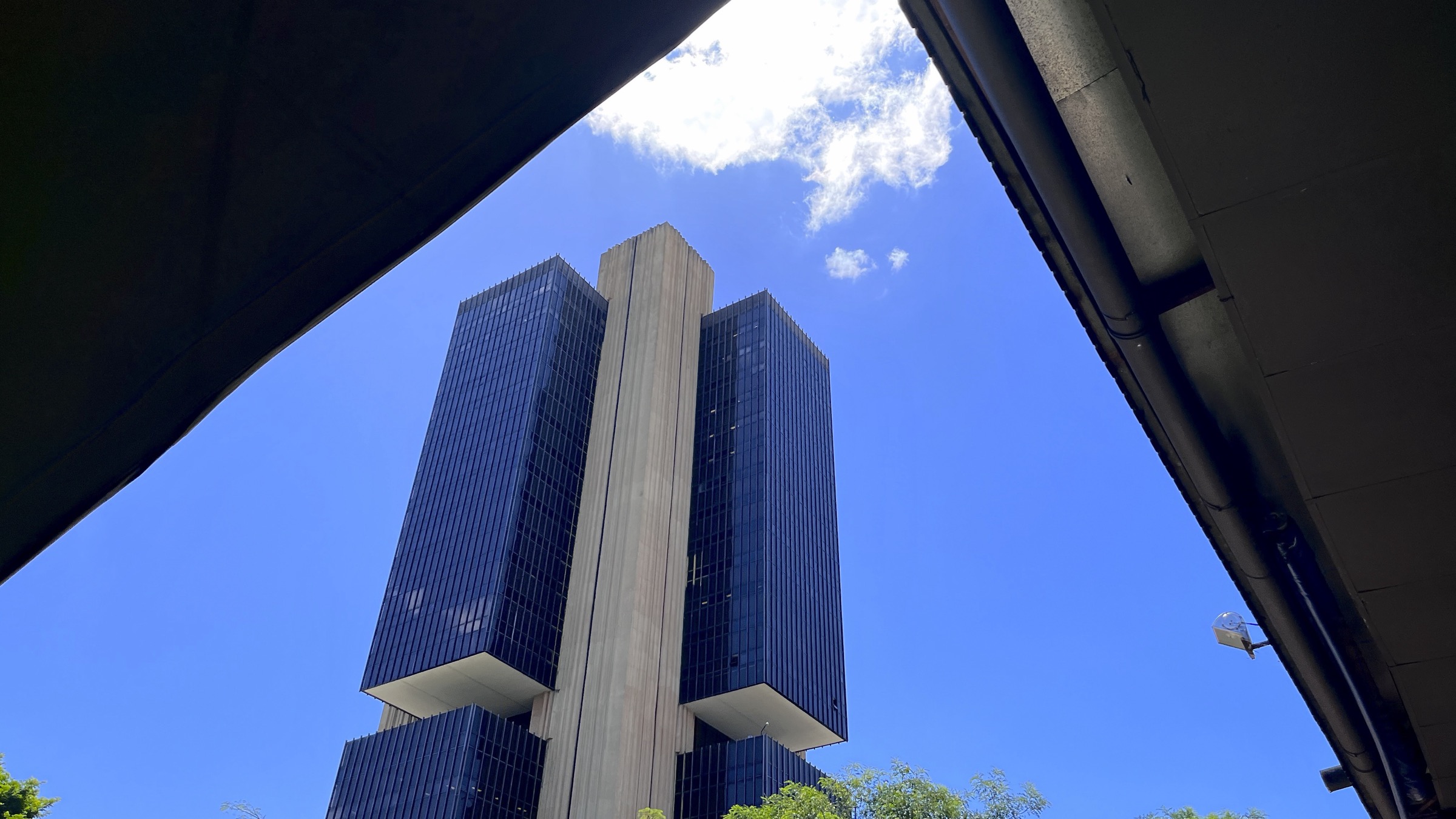 The headquarters of the Banco Central do Brasil in Brasilia, a tall dark glass tower seen from below against a blue sky