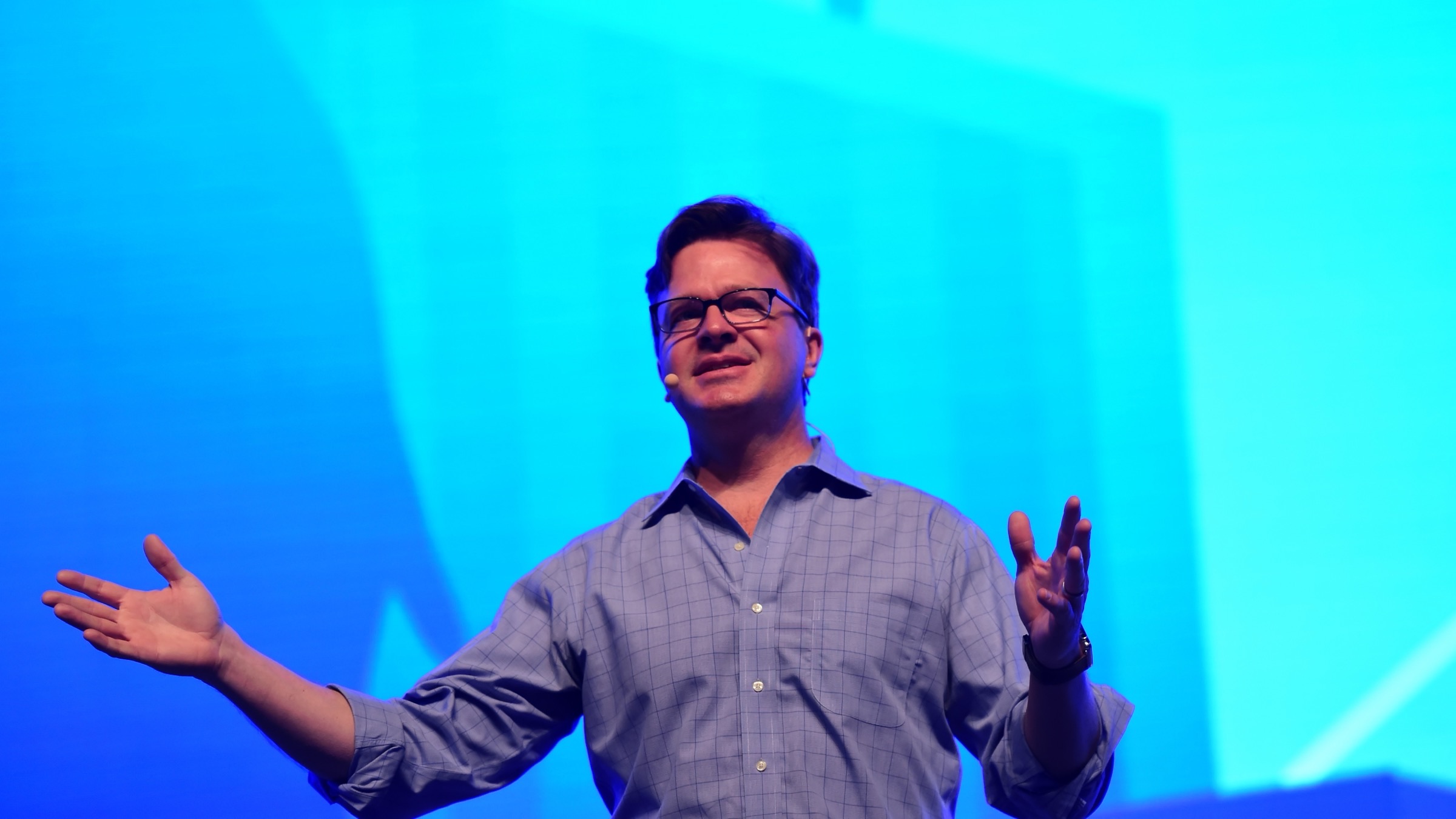 Jim Zemlin, chief executive of the Linux Foundation, speaks onstage with both hands raised against a blue backdrop while delivering a keynote at LinuxCon China in Beijing in 2017.
