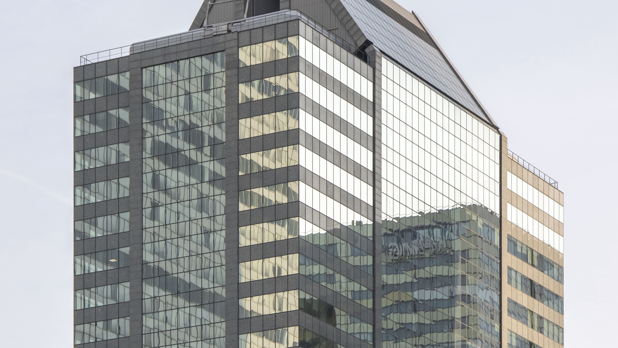 The upper floors of Tour Europlaza, a glass office tower in the La Defense business district of Paris, seen against an overcast sky.