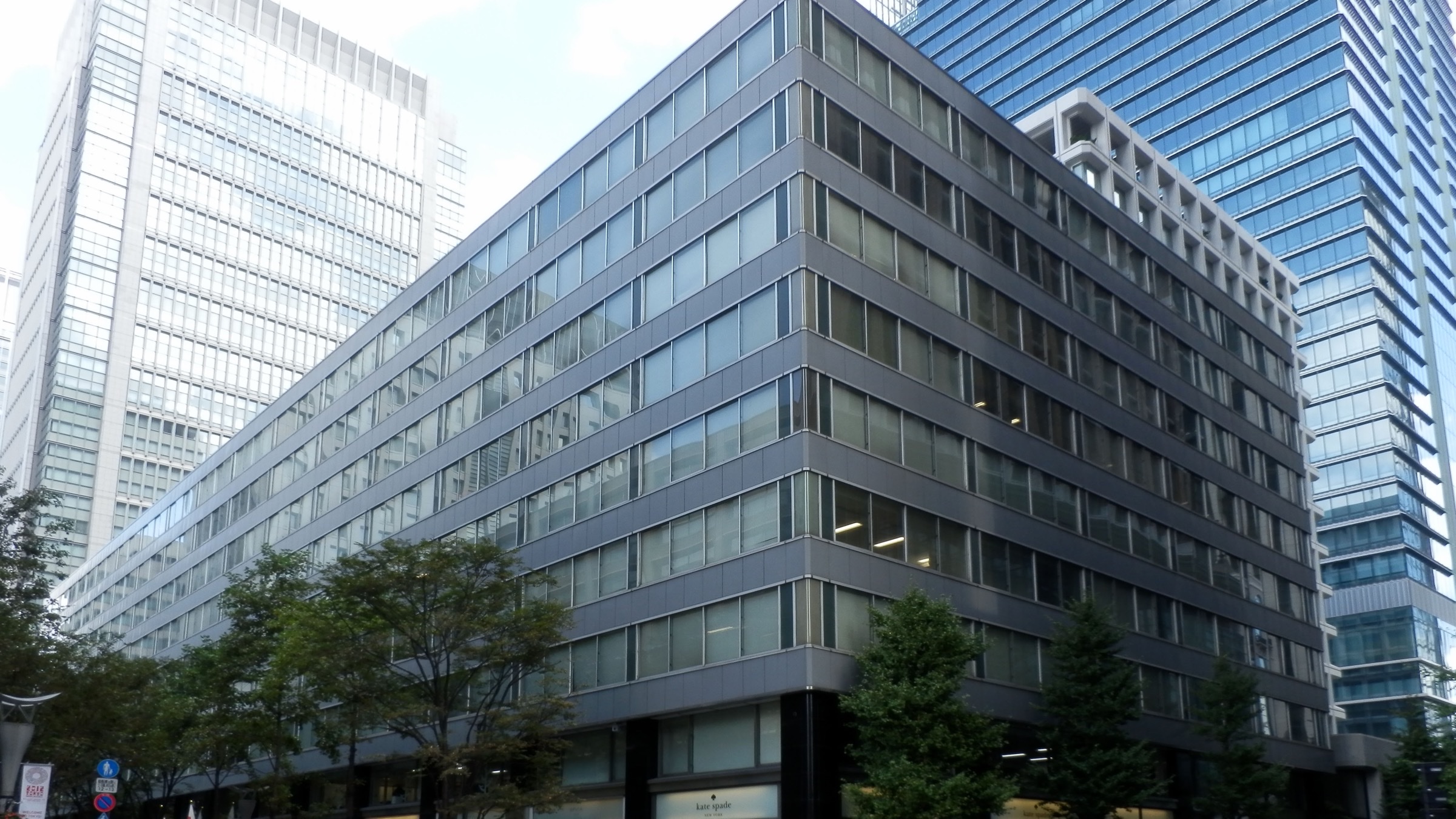 Office buildings in the Marunouchi business district of Tokyo, with pedestrians crossing at street level.