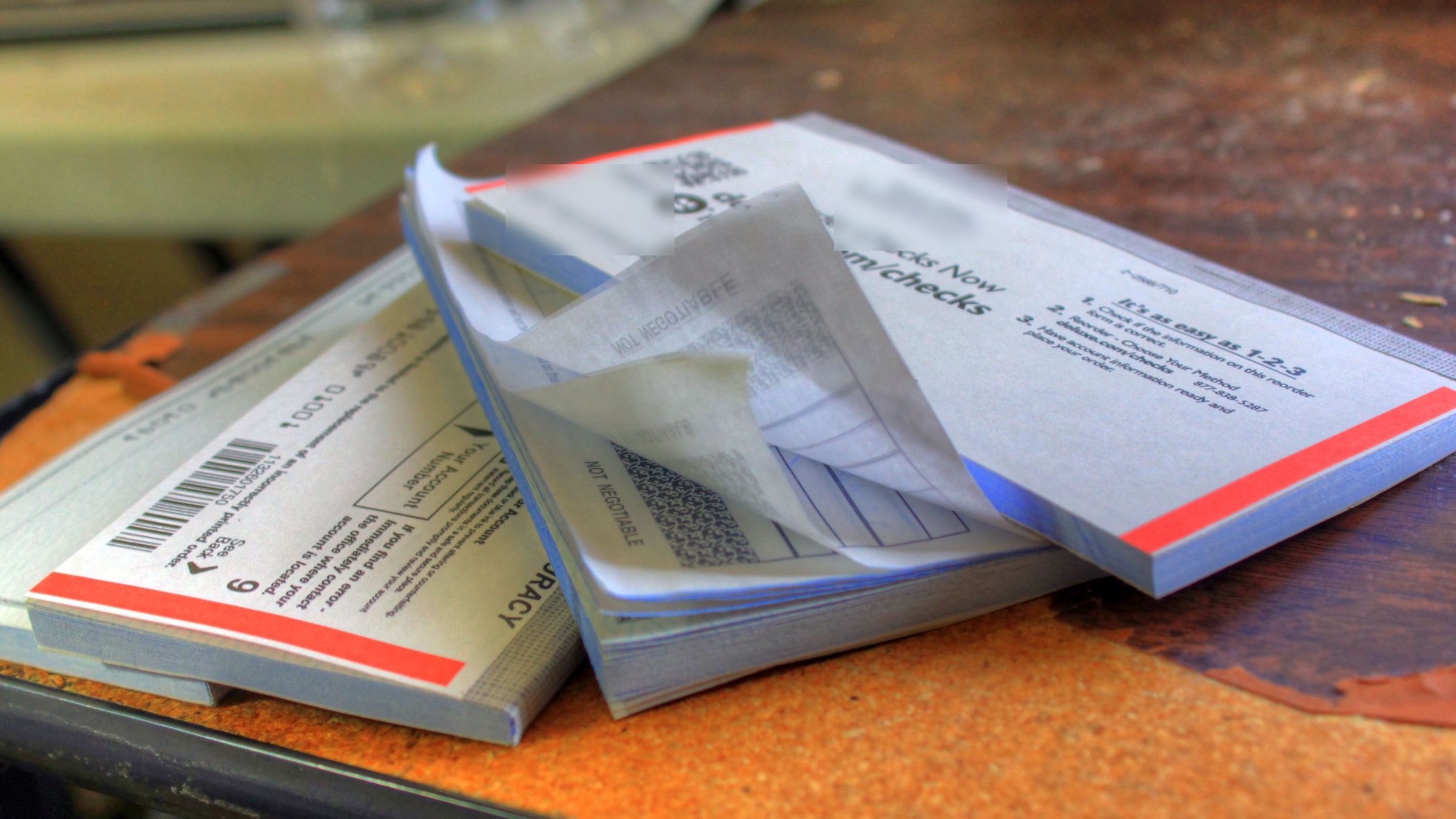 Two US checkbooks lying open on a wooden desk, with check stubs and reorder forms visible