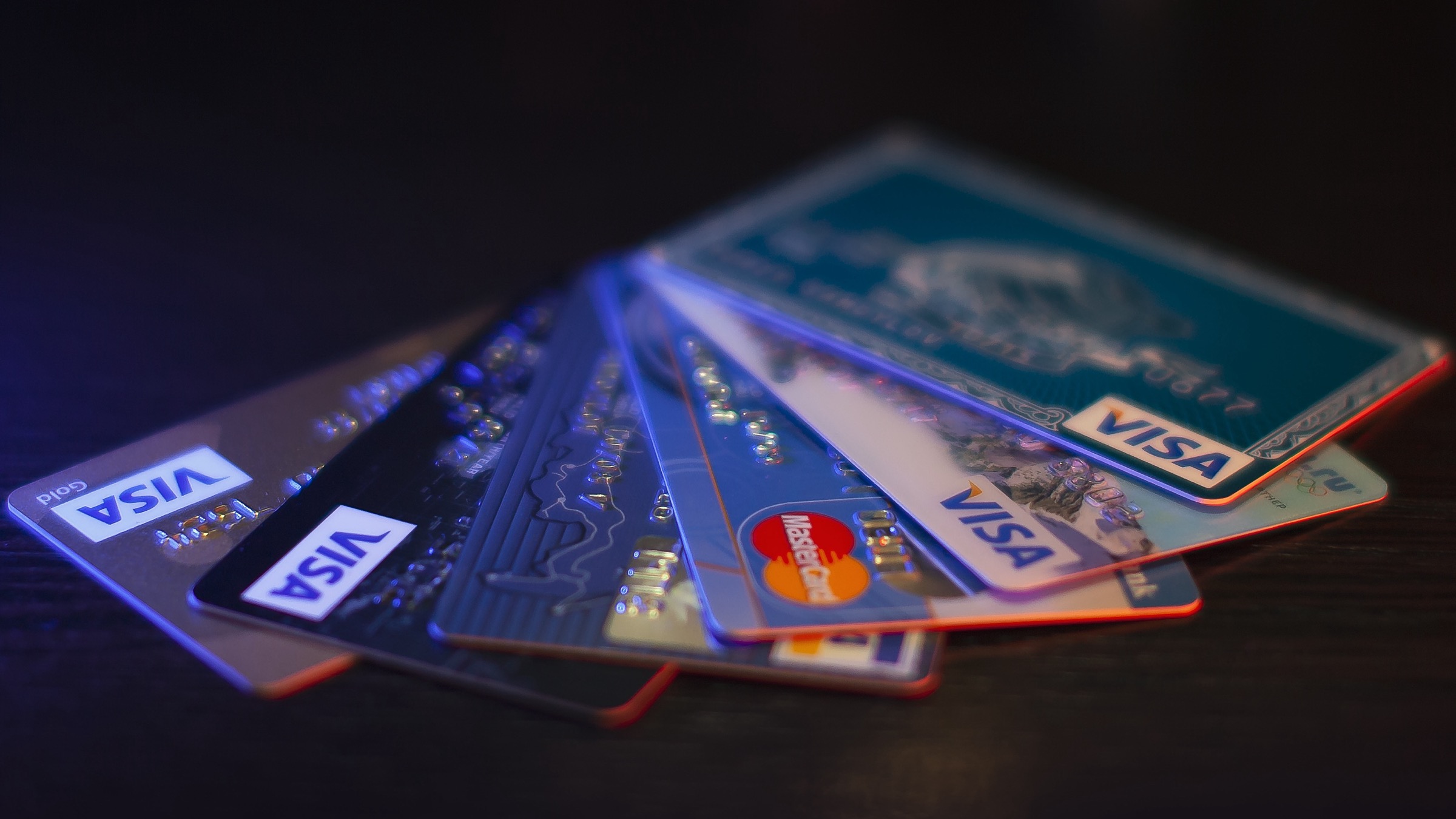 A fan of Visa and Mastercard credit cards on a dark surface, photographed at close range