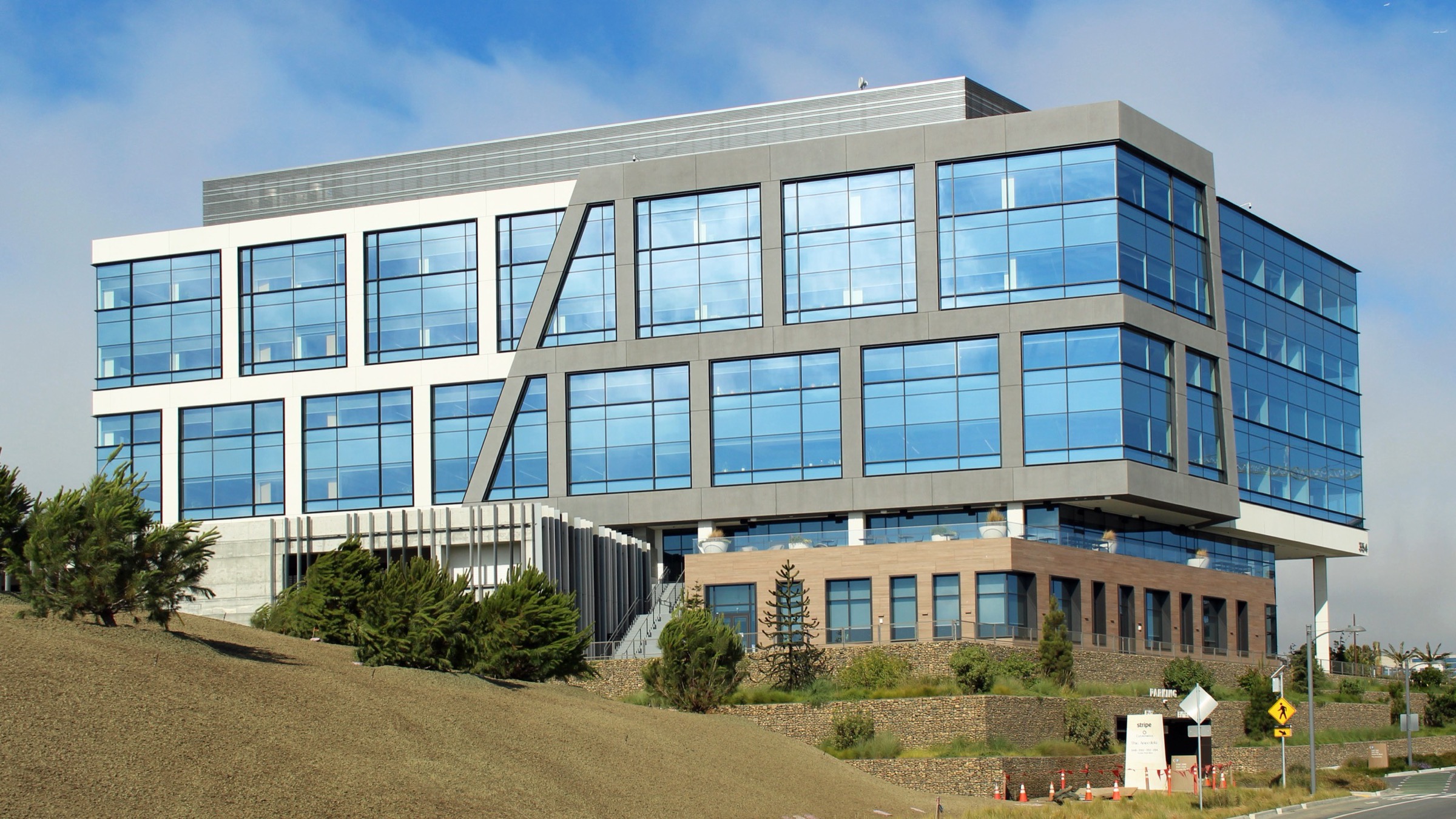 Stripe’s glass-fronted headquarters building on a hillside in South San Francisco, California, under a blue sky